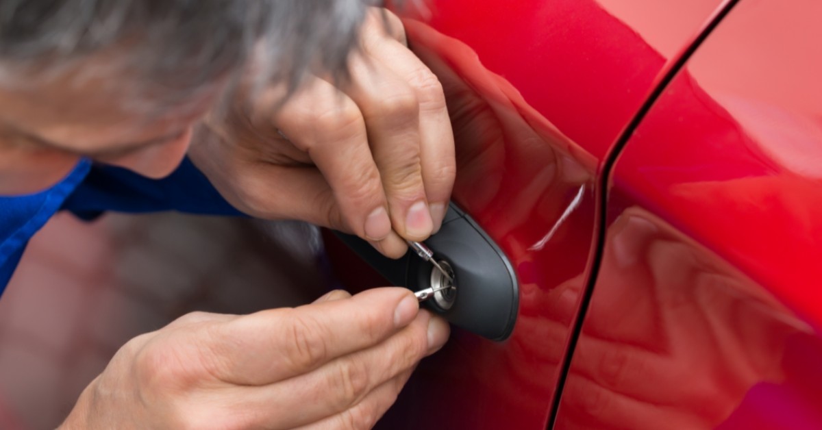 Image of a car locksmith helping with an emergency lockout on a red vehicle.